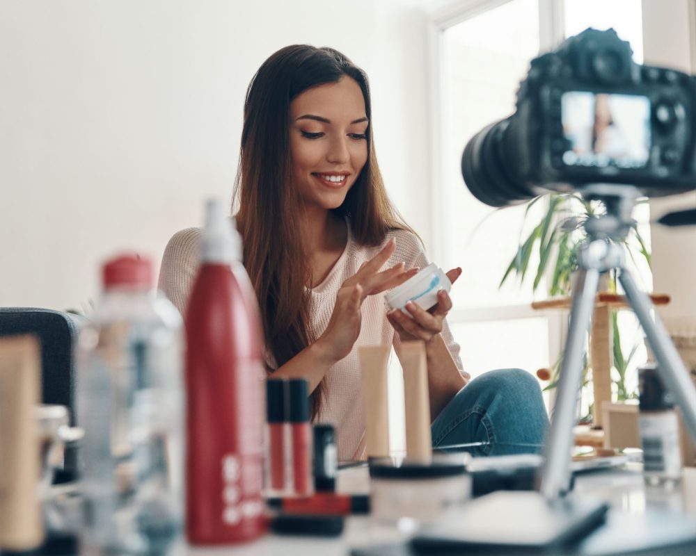 vecteezy_happy-young-woman-applying-lip-gloss-and-smiling-while_13451167